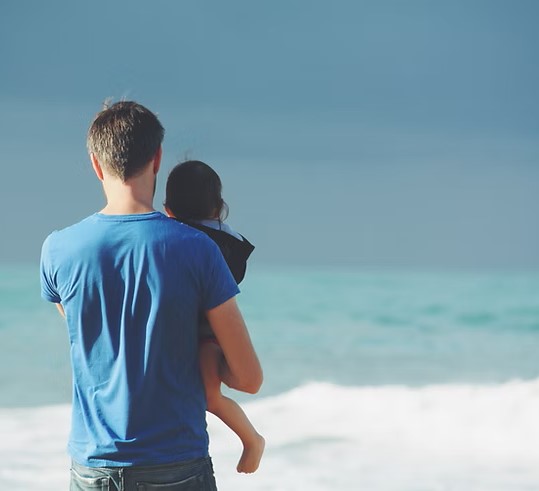 Father holding his young child on a beach